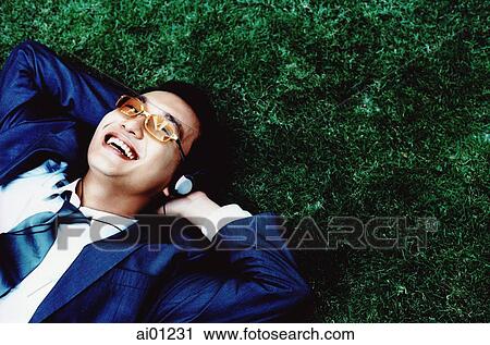Male executive with headphones lying on grass, smiling ( high grain) View Large Photo Image Stock Image - Male executive with headphones lying on grass, smiling ( high grain). Fotosearch