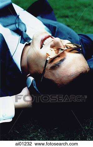 Male executive with headphones lying on grass, smiling ( high grain) View Large Photo Image Stock Image - Male executive with headphones lying on grass, smiling ( high grain). Fotosearch