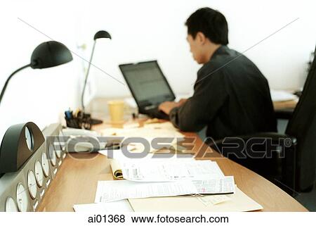 Stock Photo - Male executive working on laptop, rearview.. Fotosearch