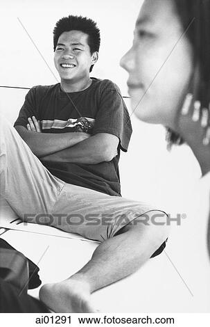 Stock Image - Male teenager smiling, female teenager in foreground. Fotosearch