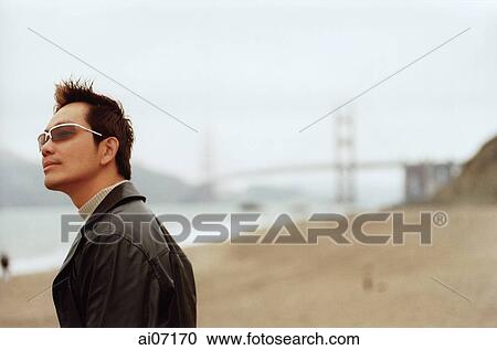 Man at beach, wearing jacket and sunglasses View Large Photo Image Stock Image - Man at beach, wearing jacket and sunglasses. Fotosearch