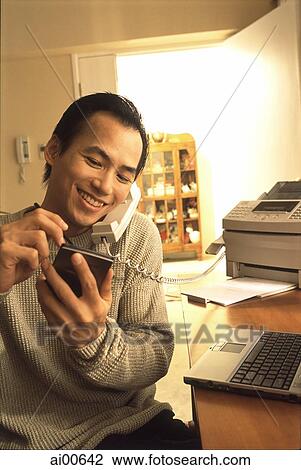 Man at home talking on telephone, holding palmtop View Large Photo Image Stock Image - Man at home talking on telephone, holding palmtop. Fotosearch