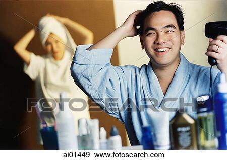 Man blow drying hair, woman with towel on head in background View Large Photo Image Stock Photo - Man blow drying hair, woman with towel on head in background. Fotosearch