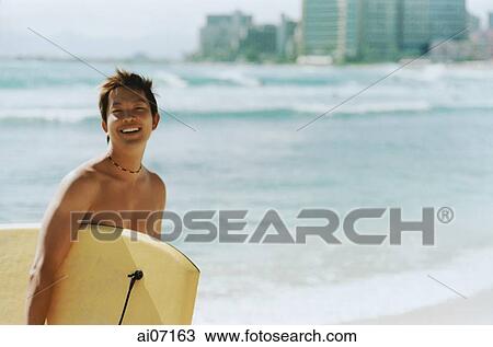 Man carrying wakeboard by beach View Large Photo Image Stock Image - Man carrying wakeboard by beach. Fotosearch