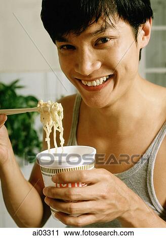 Stock Image - Man eating instant noodles. Fotosearch