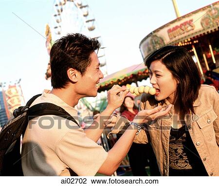 Man feeding fishballs to woman at carnival. View Large Photo Image Stock Image - Man feeding fishballs to woman at carnival.. Fotosearch