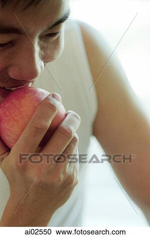 Stock Image - Man holding apple up to mouth. Fotosearch