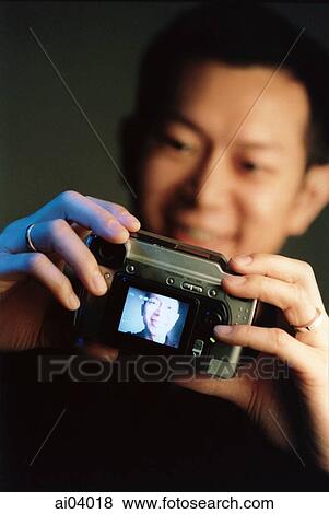 Stock Photo - Man holding digital camera, black background ( high grain). Fotosearch