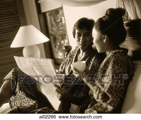 Man holding newspaper in bed talking with woman holding cup View Large Photo Image Stock Photograph - Man holding newspaper in bed talking with woman holding cup. Fotosearch