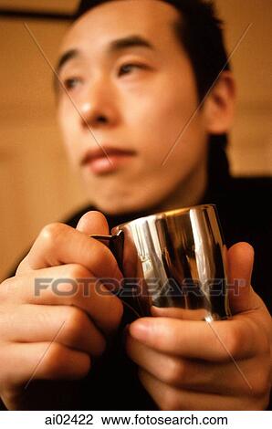 Stock Image - Man holding silver cup looking off camera.. Fotosearch