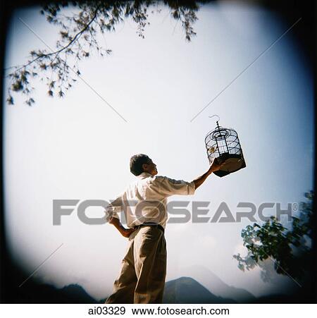 Stock Photo - Man holding up birdcage. Fotosearch