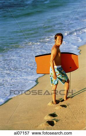 Man holding wakeboard by beach View Large Photo Image Stock Photo - Man holding wakeboard by beach. Fotosearch