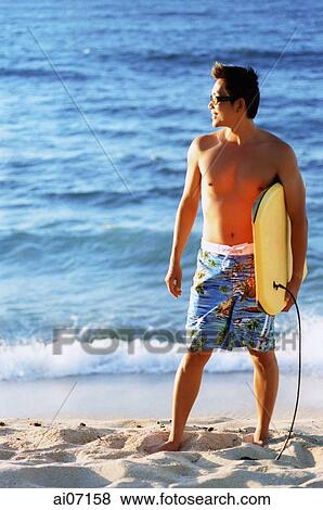 Man holding wakeboard by beach View Large Photo Image Stock Photo - Man holding wakeboard by beach. Fotosearch