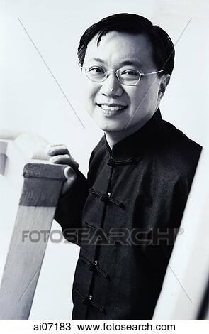 Stock Image - Man in Chinese suit smiling, hand resting on pillar.. Fotosearch