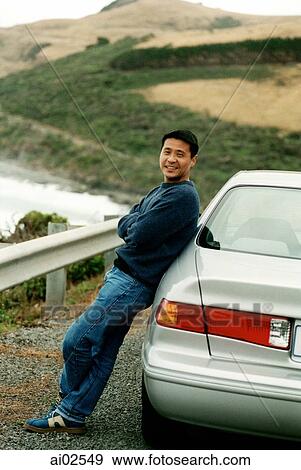 Man leaning on car, beach and hills in background View Large Photo Image Stock Photo - Man leaning on car, beach and hills in background. Fotosearch