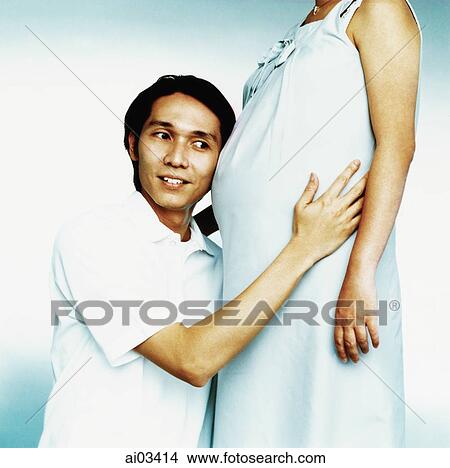 Man listening to stomach of pregnant woman View Large Photo Image Picture - Man listening to stomach of pregnant woman. Fotosearch
