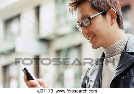Stock Image - Man looking at mobile phone. Fotosearch