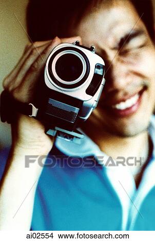 Picture - Man looking into viewfinder of camcorder. Fotosearch