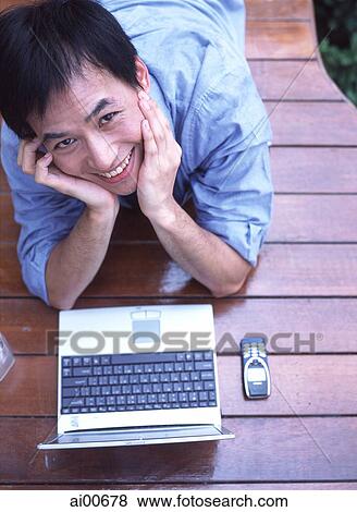Stock Photo - Man lying down with hands supporting head, portrait, elevated view. Fotosearch