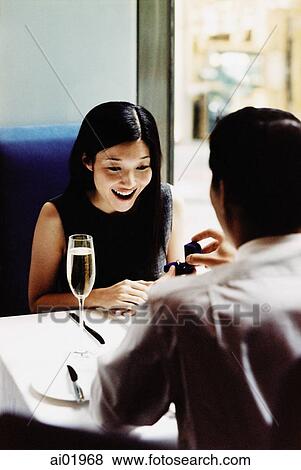 Man presenting engagement ring to woman in restaurant View Large Photo Image Stock Photo - Man presenting engagement ring to woman in restaurant. Fotosearch