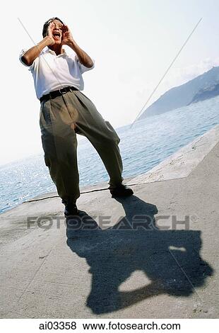 Man shouting on beach, sea in background View Large Photo Image Stock Photo - Man shouting on beach, sea in background. Fotosearch