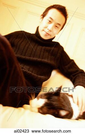Stock Image - Man sitting and petting cat.. Fotosearch
