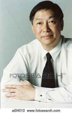 Man sitting at table with arms folded, portrait View Large Photo Image Stock Image - Man sitting at table with arms folded, portrait. Fotosearch