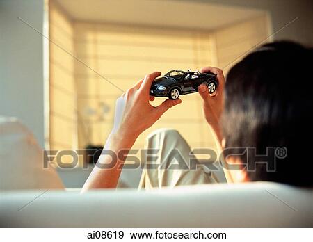 Man sitting, holding toy model car, back view. View Large Photo Image Stock Photo - Man sitting, holding toy model car, back view.. Fotosearch