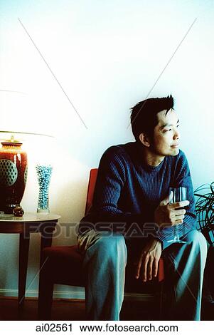 Man sitting in living room holding wineglass looking off camera View Large Photo Image Stock Image - Man sitting in living room holding wineglass looking off camera. Fotosearch