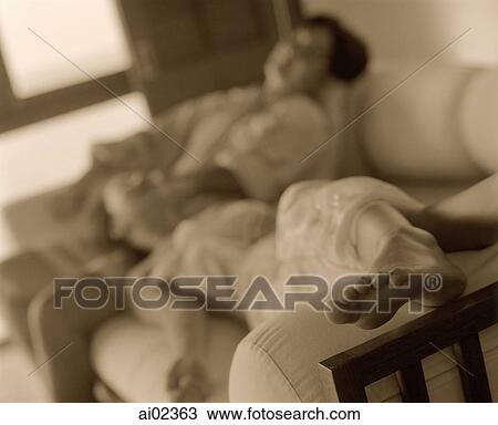 Man sitting on sofa, woman lying down with head on lap, focus on feet View Large Photo Image Stock Image - Man sitting on sofa, woman lying down with head on lap, focus on feet. Fotosearch