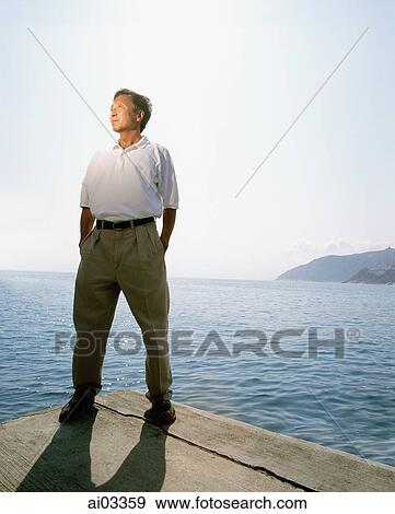 Man standing by sea View Large Photo Image Stock Photo - Man standing by sea. Fotosearch