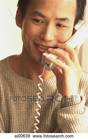 Stock Photo - Man talking on telephone, smiling. Fotosearch
