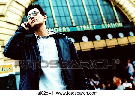 Man using cellular phone, train station in background View Large Photo Image Stock Image - Man using cellular phone, train station in background. Fotosearch