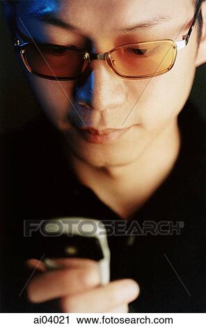 Man wearing glasses holding cellular phone View Large Photo Image Stock Image - Man wearing glasses holding cellular phone. Fotosearch