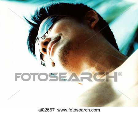 Stock Photo - Man wearing sunglasses, low view. Fotosearch