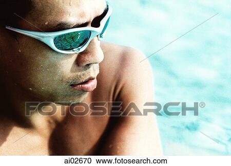 Man wearing sunglasses sitting by pool View Large Photo Image Stock Image - Man wearing sunglasses sitting by pool. Fotosearch