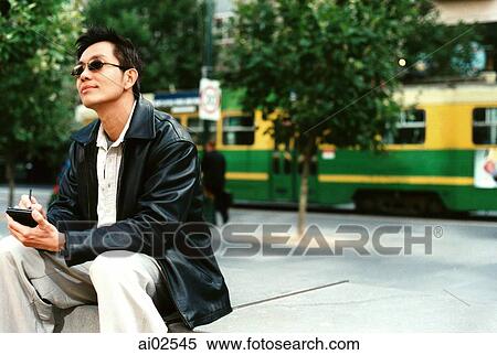 Man wearing sunglasses using PDA, street tram in background View Large Photo Image Stock Photography - Man wearing sunglasses using PDA, street tram in background. Fotosearch