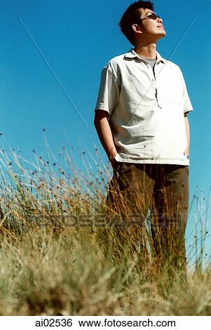 Man with sunglasses looking off camera, blue sky in background View Large Photo Image Stock Photograph - Man with sunglasses looking off camera, blue sky in background. Fotosearch