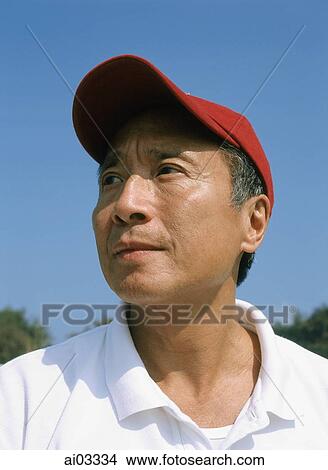 Picture - Mature man with red cap, outdoors, looking off camera. Fotosearch