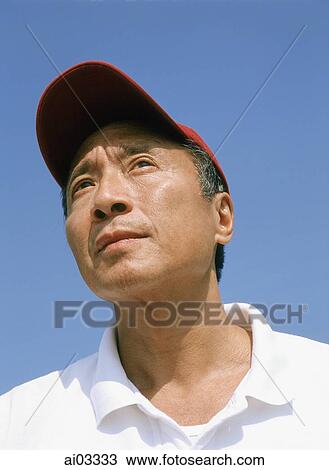 Stock Image - Mature man with red cap, outdoors, looking off camera. Fotosearch