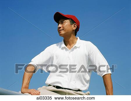 Stock Photography - Mature man with red cap, outdoors, looking off camera. Fotosearch