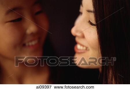 Stock Photo - Mother and daughter looking at each other and smiling. Fotosearch