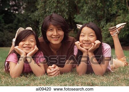 Mother and two daughters lying on grass View Large Photo Image Stock Image - Mother and two daughters lying on grass. Fotosearch