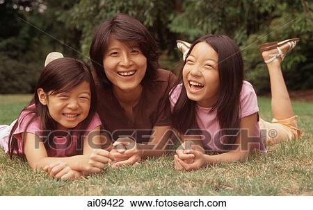 Mother and two daughters lying on grass View Large Photo Image Stock Image - Mother and two daughters lying on grass. Fotosearch