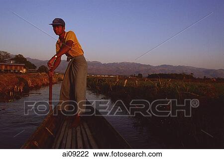 Myanmar (Burma), Inle lake, Boatman dressed in longyi steering canoe down backwaters. View Large Photo Image Stock Image - Myanmar (Burma), Inle lake, Boatman dressed in longyi steering canoe down backwaters.. Fotosearch