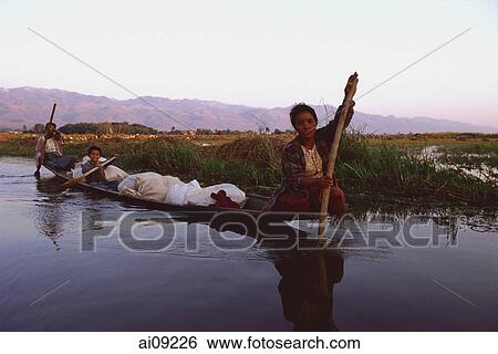 Stock Photograph - Myanmar (Burma), Inle lake, Women steering their laden canoe through backwaters.. Fotosearch