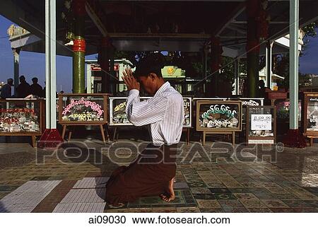 Stock Image - Myanmar (Burma), Kyaiktiyo, Buddhist pilgrim praying at 'golden rock'.. Fotosearch