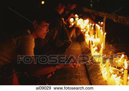 Stock Photo - Myanmar (Burma), Kyaiktiyo, Buddhist pilgrims lighting candles at 'golden rock'.. Fotosearch