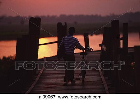 Myanmar (Burma), Mandalay, Man with bicycle crossing the U Bein bridge at sunset. View Large Photo Image Stock Photo - Myanmar (Burma), Mandalay, Man with bicycle crossing the U Bein bridge at sunset.. Fotosearch