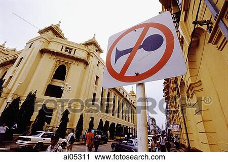 Stock Image - Myanmar (Burma), Yangon (Rangoon), A No Horns sign near the side of the road, colonial buildings in background.. Fotosearch